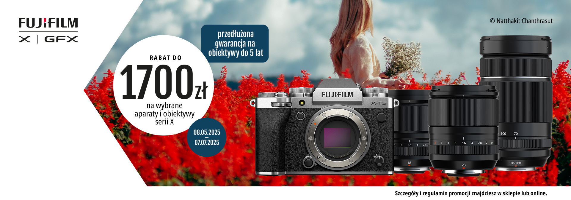 Aparat Fujifilm X-T5 i obiektywy serii X na tle pola czerwonych kwiatów, kobieta w tle trzyma bukiet